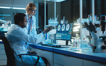 A female researcher and a male researcher look at a computer